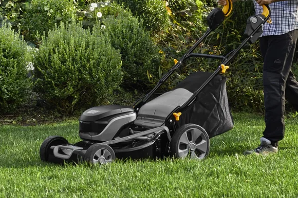 Person schiebt Rasenmäher